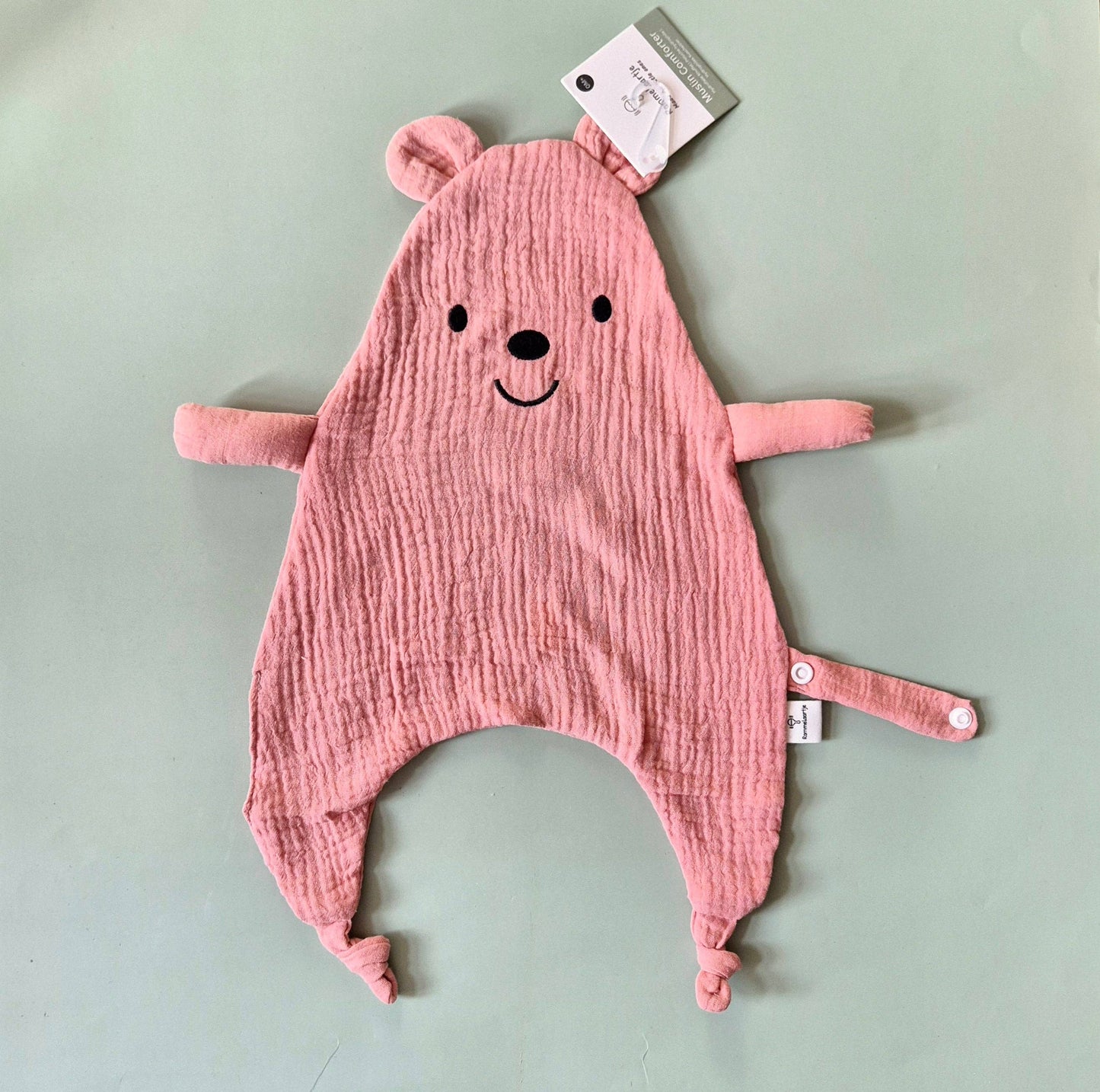 Bären-Kuscheltuch in Rosa mit kleinen Ohren und freundlichem Gesicht, flach von oben fotografiert.